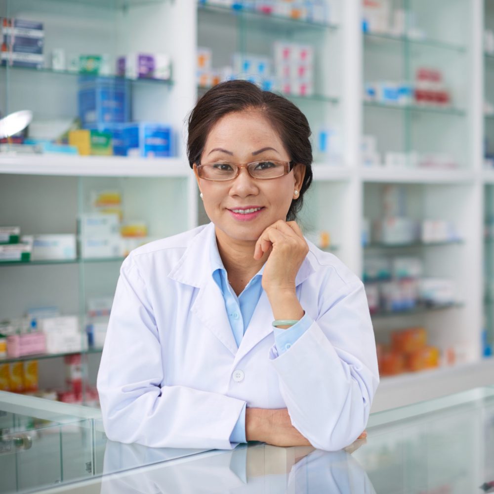 Portrait of senior Vietnamese pharmacist in drugstore